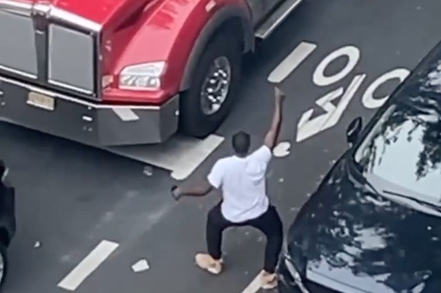 A photo of a man dancing in front of a truck